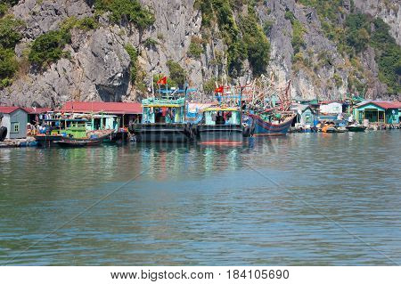 Floating fishing village with rock island in background, Ha Long bay, Vietnam.