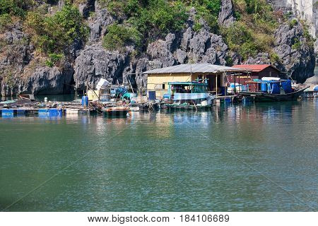 Floating fishing village with rock island in background, Ha Long bay, Vietnam.