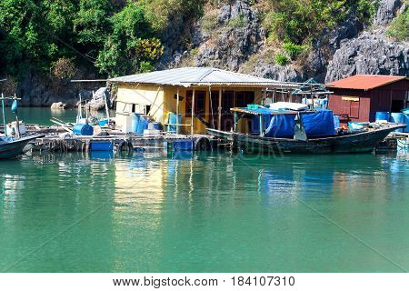 Floating fishing village with rock island in background, Ha Long bay, Vietnam.