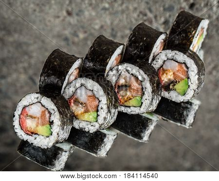Sushi roll with salmon, shrimps and avocado over cocnrete background
