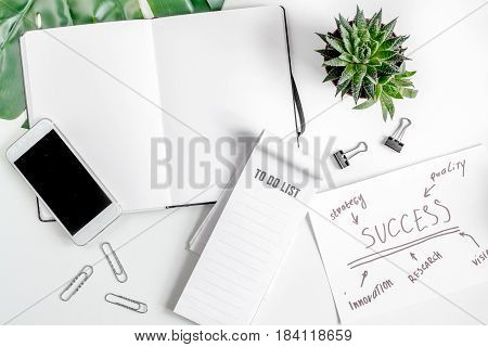 business plan development with mobile and copybook on white office desk background top view mock-up