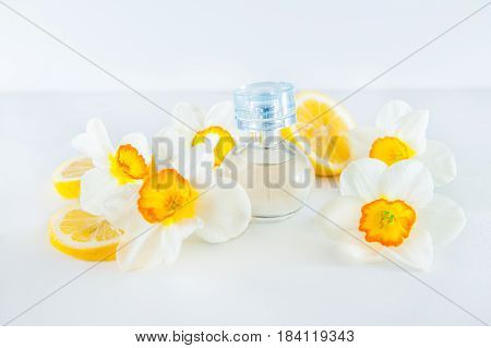 Orbicular Perfume Bottle Surrounded By Fresh Daffodils Flowers And Lemon Slices Isolated On White Ba