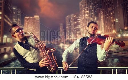 Saxophonist and violinst against night cityscape