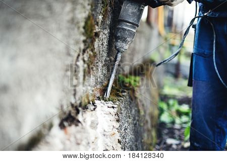Working man practicing his skills with pneumatic drill at demolishing walls