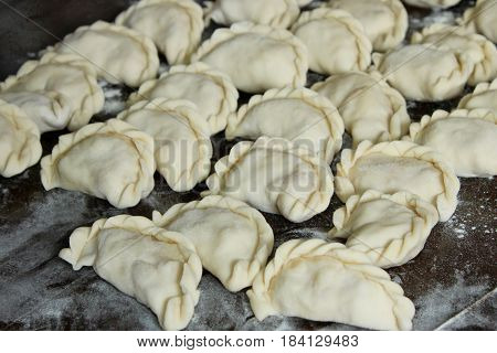 Dumplings with potatoes on the dark kitchen board. Dumplings with potatoes (or cottage cheese cabbage cherries etc.) is a traditional Ukrainian dish is also known as Varenyky or Vareniks