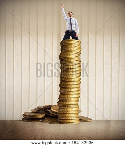 Happy businessman exults over a stack of golden coins