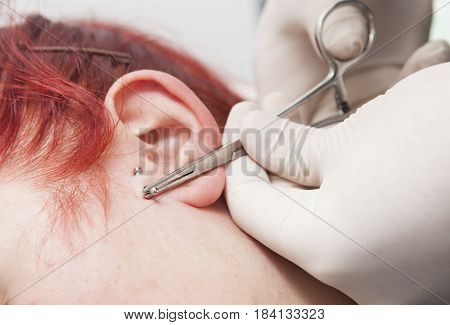 Professional placing the jewel of piercing on the ear with ball. Tragus type