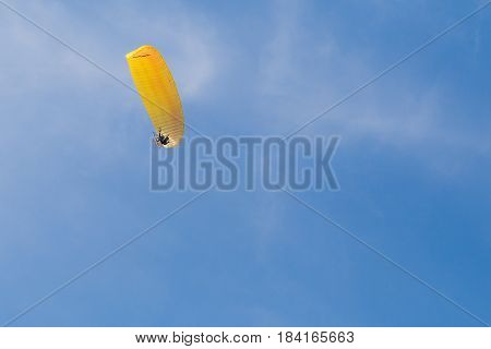 Human with paramotor flying in the blue sky