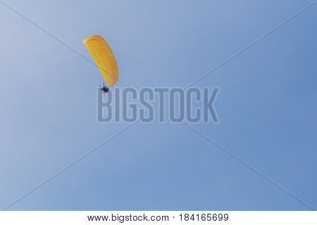 Human with paramotor flying in the blue sky