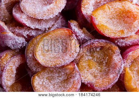 frozen half of a plum on a wooden background. Winter vitamins