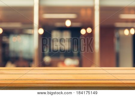 Wooden board empty table top on of blurred background. Perspective brown wood table over blur in coffee shop background - can be used mock up for montage products display or design key visual layout.