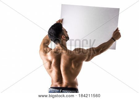 Naked young male bodybuilder holding blank white sign, isolated on white background, seen from the back, large copyspace