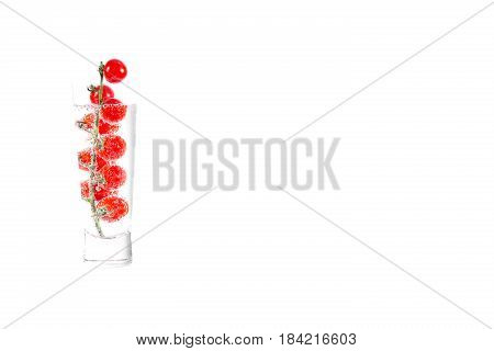 Cherry tomat in glass of mineral water, isolated on white background
