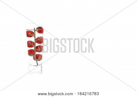 Cherry tomat in glass of mineral water, isolated on white background