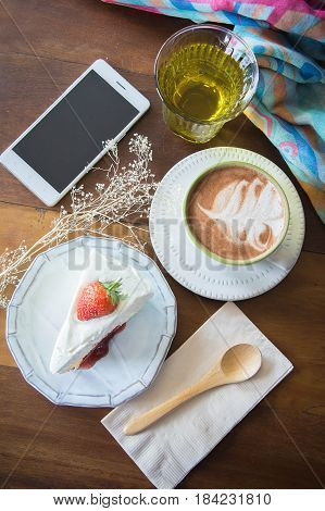coffee cup and delicious cake strawberry and relax time moblie on table in coffee shop