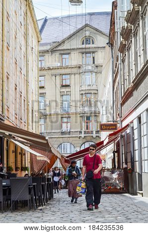 Lviv Ukraine - June 1 2013: Downtown old town architecture with cobblestone street and people walking by cafe in historical city