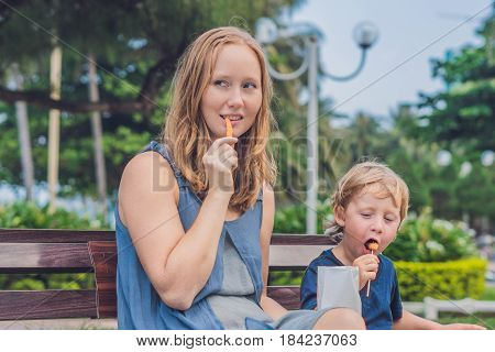 Mom And Son Eat Fried Sweet Potatoes In The Park. Junk Food Concept