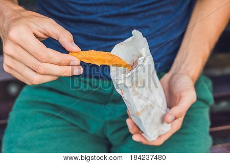 Man Eat Fried Sweet Potatoes In The Park. Junk Food Concept