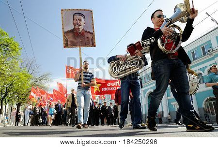 Orel Russia - May 1 2017: May demonstration. Trumpeters marching in front of crowd with Stalin portrait and red Communist flags background