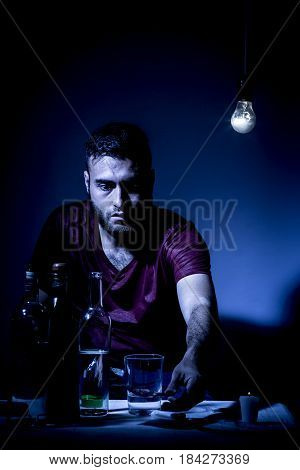 Young man with beard lost in the vices of alcoholism smoking and drug addiction