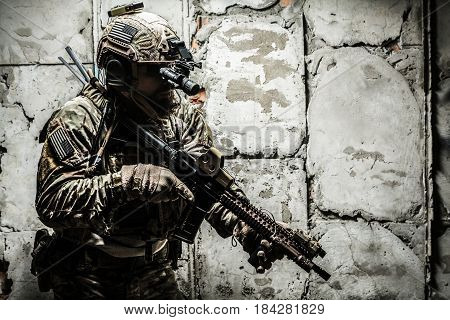 Army Ranger moving along the concrete wall on mission