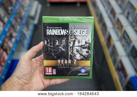 Bratislava, Slovakia, circa april 2017: Man holding Tom Clancy's Rainbow Six the Siege Year 2 gold edition videogame on Microsoft XBOX One console in store