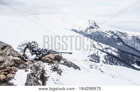 Army soldier with Sniper rifle in action in the Arctic. He lies among the cold rocks and stones, almost freezing to death, but waiting as long as enemies appear to kill them. Duty, service and loyalty