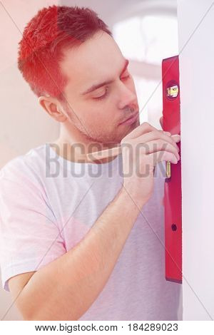 Mid-adult man marking on wall with level