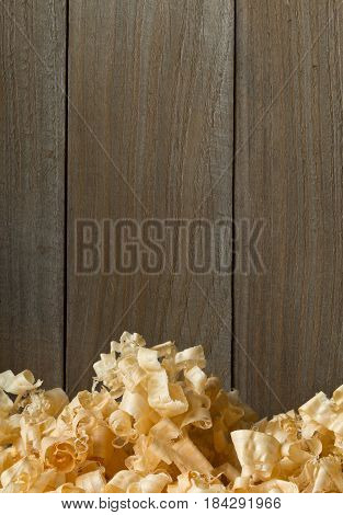 Light brown wood shavings from carpenter's hand planer or chisel work on wooden boards background with copy space