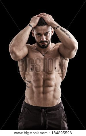 Handsome bodybuilder doing classic double biceps pose, looking away, isolated on black background