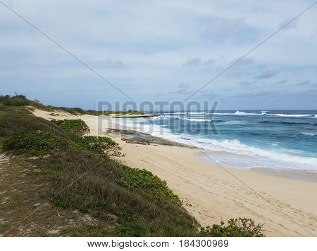 Waves break and crash towards the Hanakailio Beach with cloudy skyline on the North Shore of Oahu Hawaii.