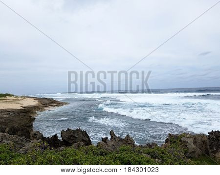 Waves break and crash towards the Kaneakua Cove with dramatic lava rock outcropping on the North Shore of Oahu Hawaii.
