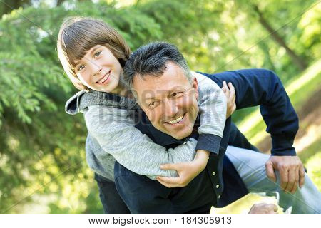 Portrait of father with his son having fun in summer park. Piggyback. Family fun. Happy boy playing with dad summer nature outdoor
