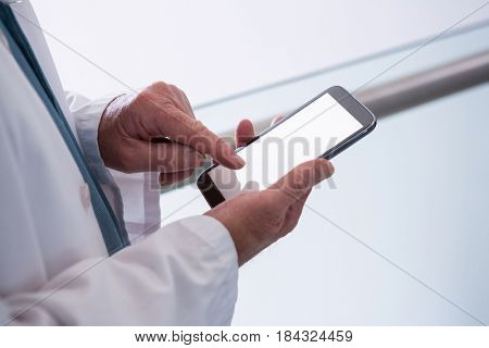 Close-up of doctor holding smartphone in the passageway at hospital