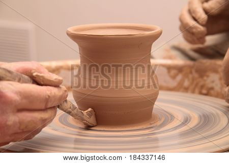 hands of a potter, creating an earthen jar on a pottery wheel