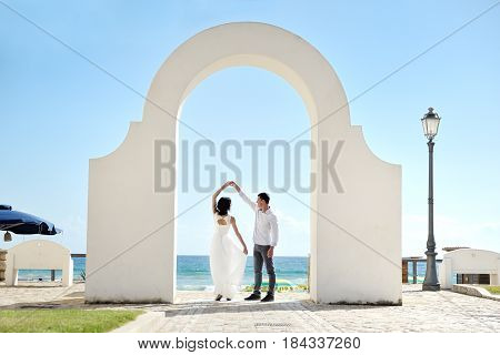 Happy couple dancing under a bow near sea in Sperlonga Italy Europe