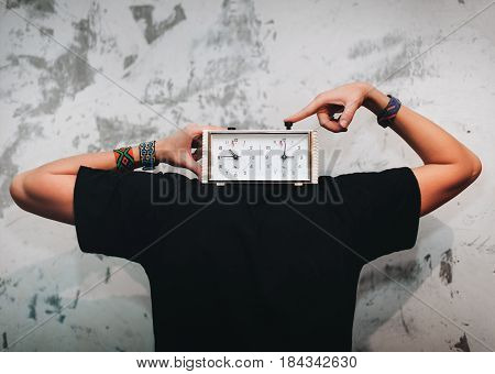Man with a chess clock instead of head on a old wall background.