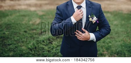 Young man in suit adjusting his necktie.