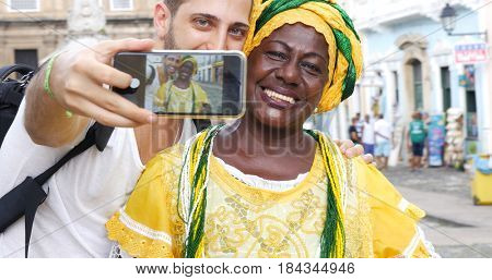 Tourist taking a selfie with a Baiana in the old colonial district of Salvador, Brazil