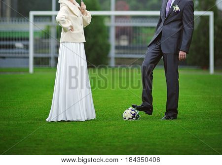 The bride and groom with a bouquet of a bride instead of a ball on a football field.