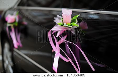Wedding black car decorated with pink flowers.