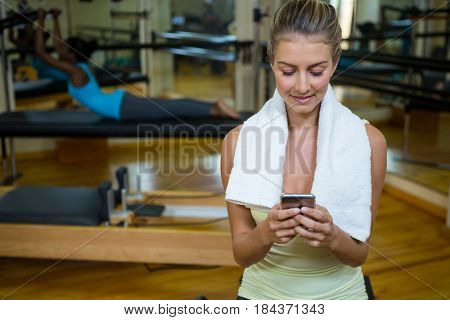 Beautiful fit woman using mobile phone after workout in gym