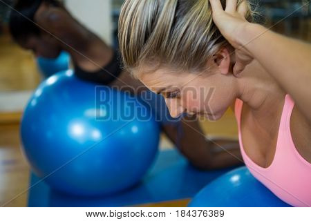 Smiling fit woman performing pilate on exercise ball in fitness studio