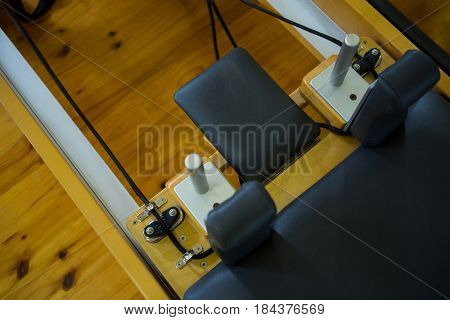 Close-up of reformer on wooden floor in gym