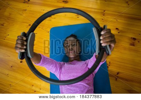 Smiling fit woman exercising with pilates ring on mat in fitness studio