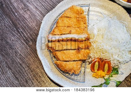 Japanese deep-fried breaded pork cullet or Tonkatsu with sliced cabbage tomato and custard