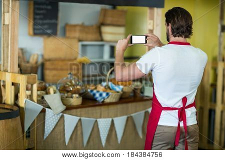 Rear view of bakery staff photographing bakery snacks and bread on the counter in bake shop