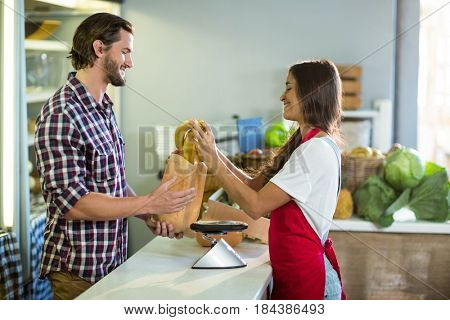 Woman vendor bananas in the paper bag at the counter in the grocery store
