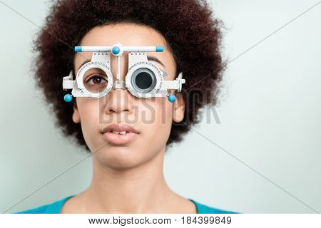 Woman having eyesight test with phoropter for new glasses at optician or eye doctor specialist