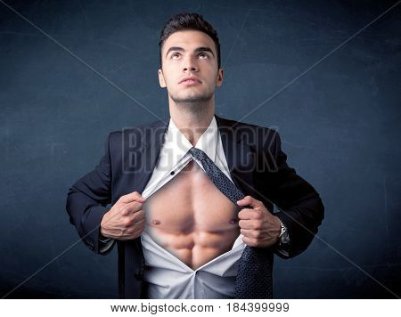 Businessman tearing off his shirt and showing mucular body concept on background